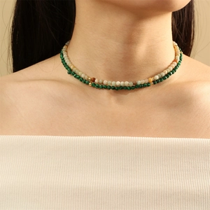 Close-up of bohemian double-layered necklace with green malachite and light natural stone beads