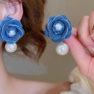 Detail of retro denim flower earrings with pearls and silver pins for stylish women