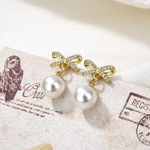 Macro shot of gold bow earrings with pearls and crystals on a vintage card