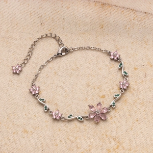 Detailed shot of silver cherry blossom bracelet with pink petals and green crystal leaves