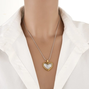 Two-tone heart pendant necklace with gold outer frame and silver striped center on a model