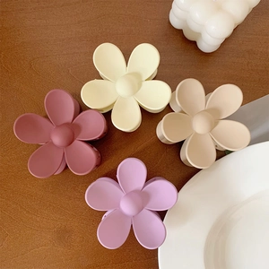 Close-up of matte flower hair claws in muted tones on a rustic wooden background