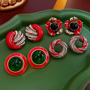 Detailed view of vintage gold-tone earrings with red enamel and crystals on a leaf tray