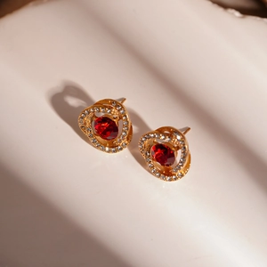 Macro view of gold flower earrings with red ruby center and sparkling micro diamonds