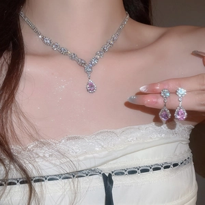 Detail shot of a sparkling pink teardrop pendant necklace and earrings set for women