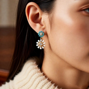 Détail de boucles d'oreilles fleurs en émail bleu et blanc portées par un mannequin