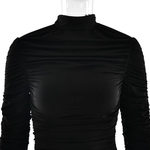 Détail de la robe noire à manches longues avec texture plissée et coupe ajustée élégante