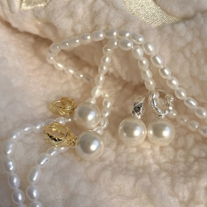 Detailed macro of quilted metal clasp pearl earrings and matching necklace on soft fabric