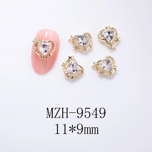 Vue macro de charms pour ongles en forme de cœur doré 11x9mm avec strass et étoiles