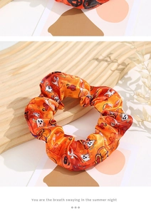 Close-up of orange satin scrunchie with Halloween ghost, cat and pumpkin patterns
