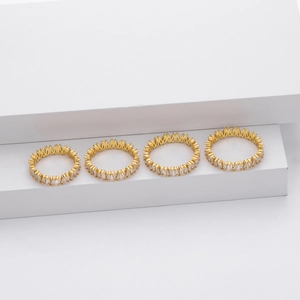 Macro detail of four gold V-shaped eternity rings with baguette cut cubic zirconia stones