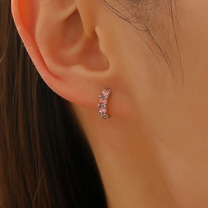 Close-up of silver hoop earring with three inlaid pink zircon stones on model's ear