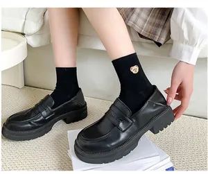 Detailed shot of black matte platform loafers paired with cute bear embroidery socks
