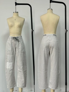 Detail of grey striped wide-leg trousers with drawstring waist and large front pockets