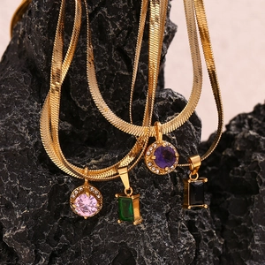 Macro detail of 18K gold-plated snake chains with colorful cubic zirconia pendants