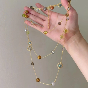 Detail view of multi-layered beaded necklace with amber, green, and smoke grey faceted beads