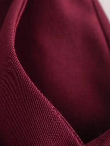 Detailed close-up of dark red ribbed knit fabric texture and high-quality seam stitching