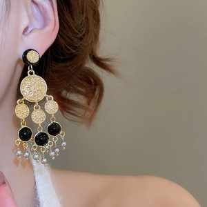 Détail de boucles d'oreilles style cour française avec émail noir et pompons de perles