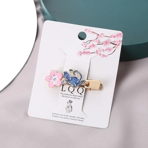 Detail view of pink cherry blossom and blue cat hair clip with sparkling rhinestones