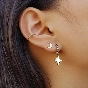 Close-up of gold ear cuff, moon stud, and blue stone star pendant earring set