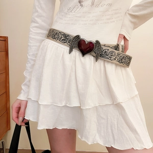 Detailed view of a vintage floral leather belt with heart wing buckle on model