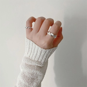Detail of a silver twisted rope ring worn on finger with a white knit sweater cuff