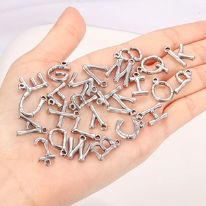 Silver stainless steel bamboo texture alphabet pendants shown in hand for size
