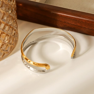 Detailed close-up of wavy two-tone gold and silver open bangle with organic hammered texture