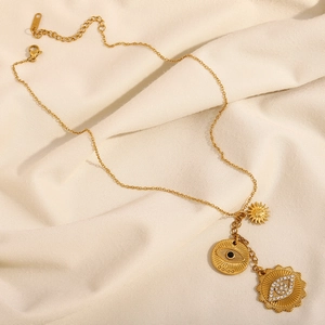 Detailed close-up of 18K gold-plated stainless steel sun and evil eye tassel pendants