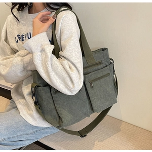 Olive green corduroy crossbody bag shown on a model with detailed ribbed texture and pockets