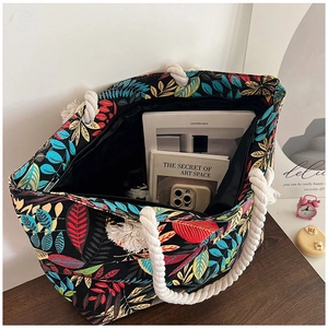 Top view of large canvas tote bag with colorful leaf patterns filled with daily essentials