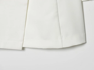 Detailed macro view showing the precise hem stitching on a white waist-defining dress