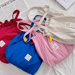 Détails macro des sacs cabas plissés en quatre couleurs avec étiquettes de marque tissées