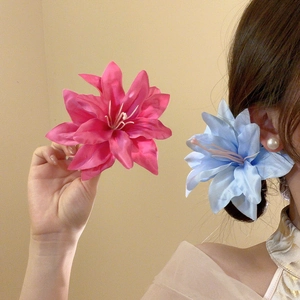 Detail of pink and blue silk lily flower hair clips showing fabric texture and petals