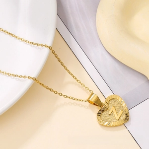 Close-up of gold heart pendant with embossed letter Z and radial texture on a link chain