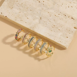 Detail of 14K gold plated rings with zircon and colorful gemstones on stone background