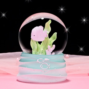 Luminous crystal ball with pink fish and green seaweed on a blue wave base