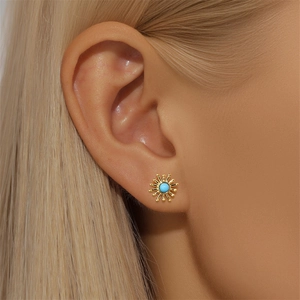 Detail view of s925 silver sun-shaped stud earring with sky blue stone on ear