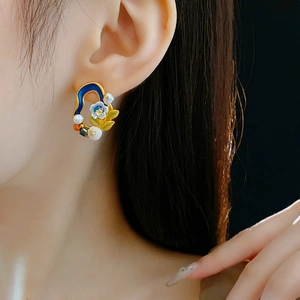 Detailed view of vintage gold floral earrings with pearls and blue accents on a model