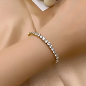 Detailed close-up of a sparkling gold tennis bracelet with cubic zirconia on silk fabric