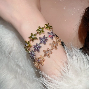 Close-up of elegant flower bracelets with green, purple, and champagne stones on white fur