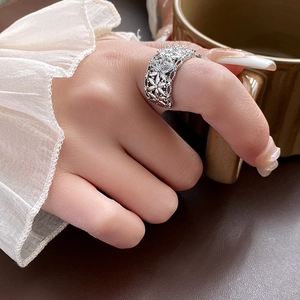 Détail d'une bague florale ajourée en argent avec zircons portée par une femme