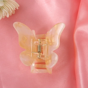 Detail of peach pink butterfly hair claw with gold glitter and metal spring on silk