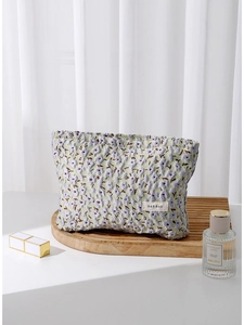 Green floral jacquard makeup bag with purple flower embroidery on a wooden tray