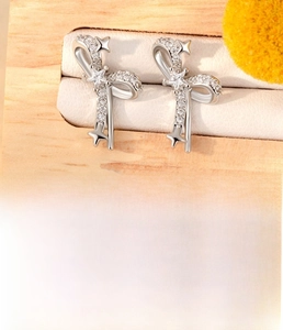 Macro view of silver titanium steel bow star stud earring with zircon and disc back