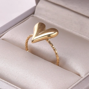 Close-up of golden heart ring with textured diamond-cut band in a velvet jewelry box