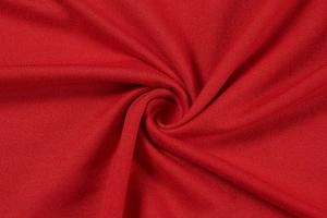 Close-up of red knitted cotton fabric texture with spiral folds and soft drape