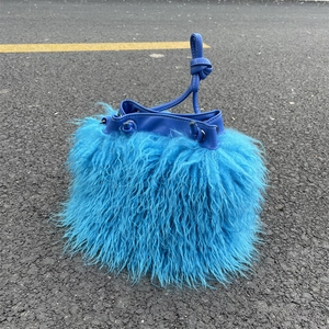 Vue de dessus d'un sac seau bleu en fausse fourrure avec cordon en cuir PU sur asphalte