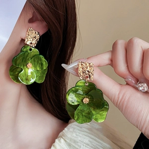Close-up of vintage green flower earrings with gold textured base on model