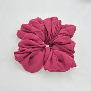 Detail shot of a soft rose red chiffon scrunchie with rich fabric folds on white background